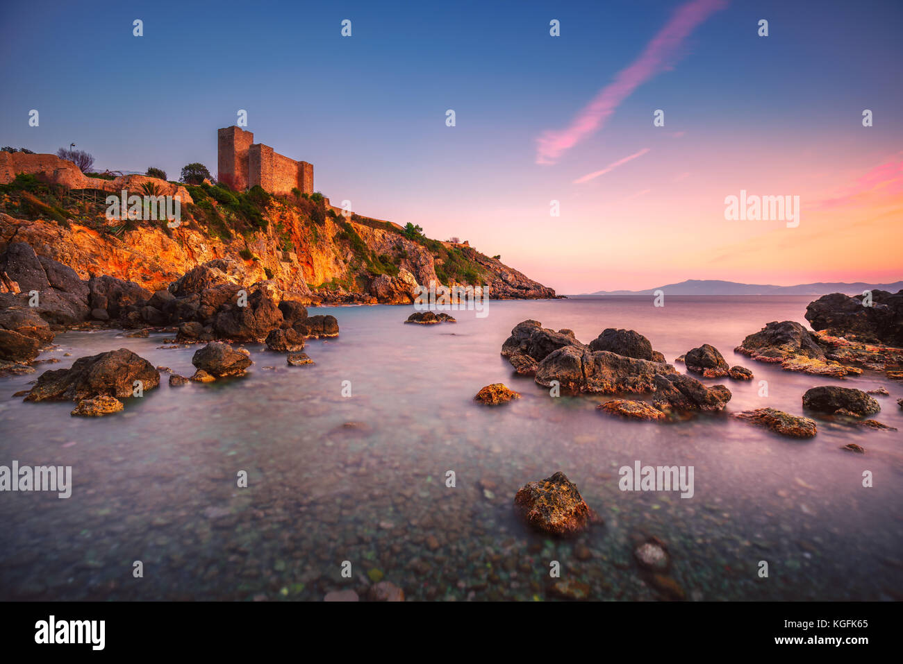 Talamone la spiaggia di roccia e fortezza medievale rocca aldobrandesca pareti e al tramonto. maremma argentario viaggi italiani di destinazione. toscana, italia. Foto Stock