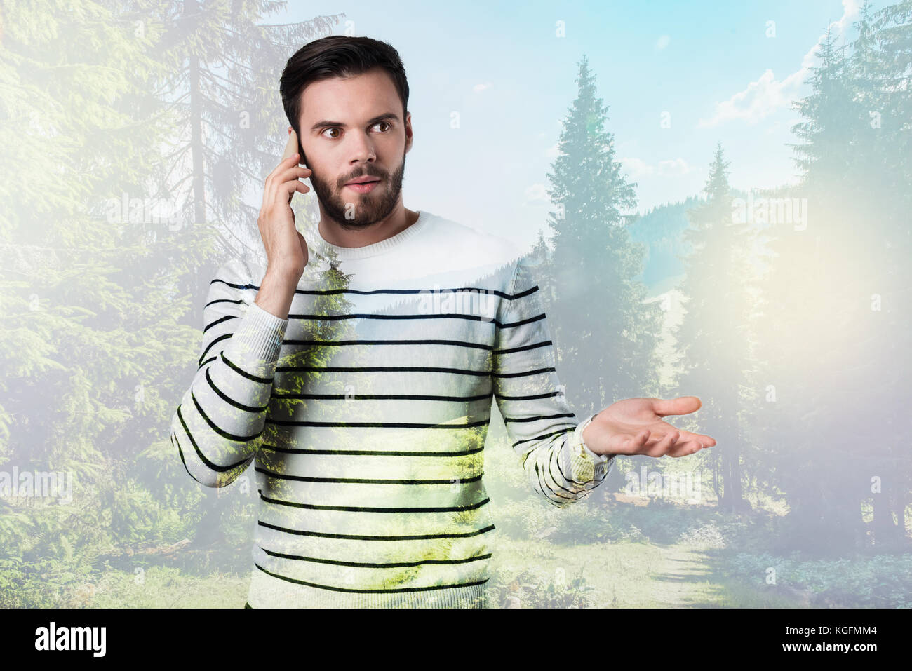 Emotional giovane uomo cercando sorpreso mentre si parla al telefono Foto Stock