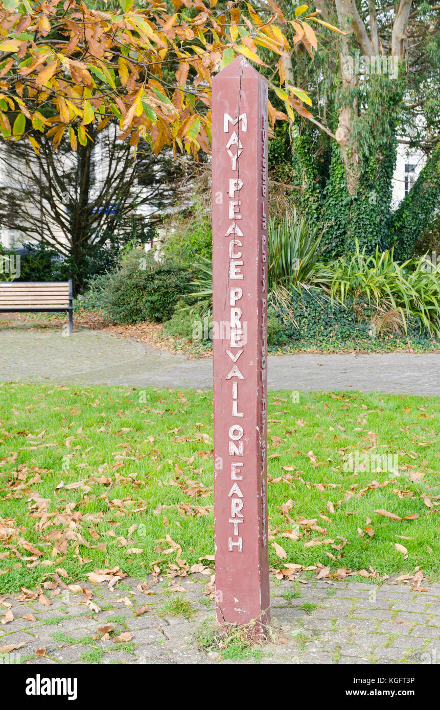 Palo di legno con la dicitura ""che la pace trionfi sulla terra' nel giardino sensoriale vicino a Plymouth Hoe, Devon Foto Stock