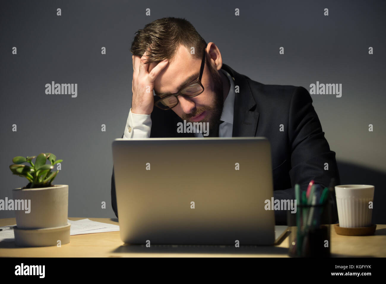 Troppo lavoro concetto. turbato l uomo con gli occhiali lettura circa il problema recente sul computer portatile, nel profondo pensiero circa il miglior corso di azioni. mano su Foto Stock