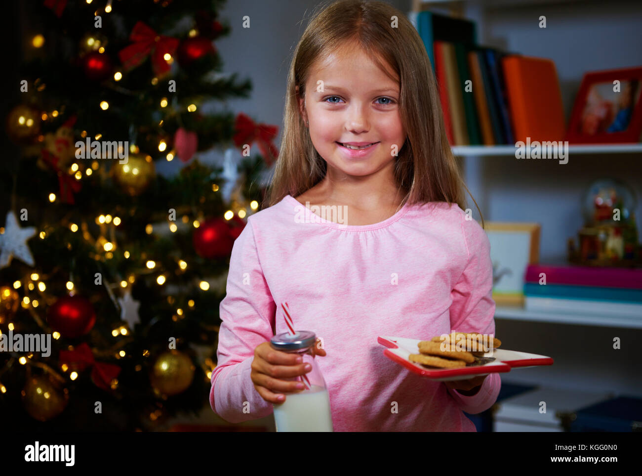 Ragazza con cookie e latte in attesa di Babbo Natale Foto Stock