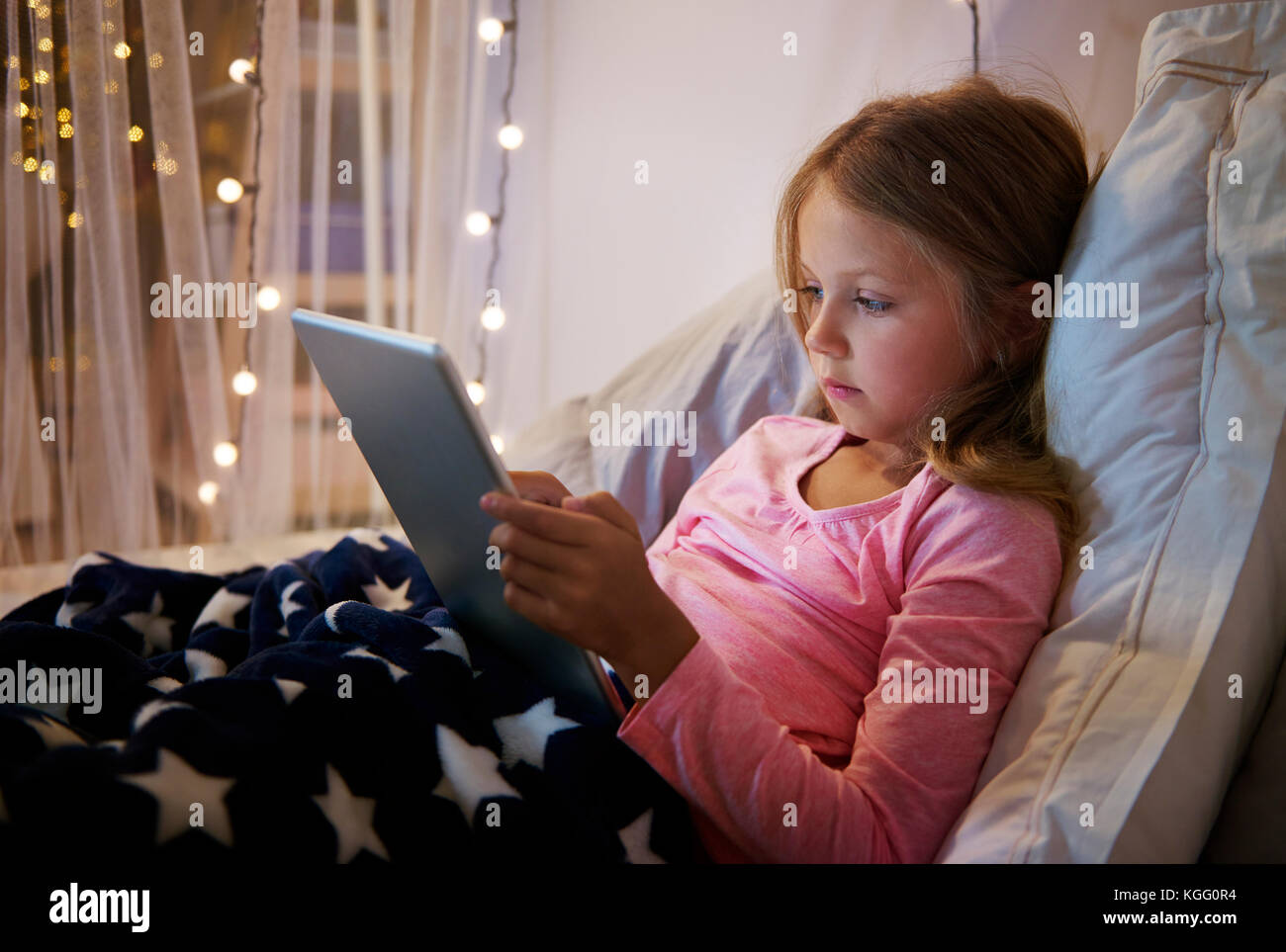 Ragazza distesa sul suo letto mentre si utilizza una tavoletta digitale Foto Stock