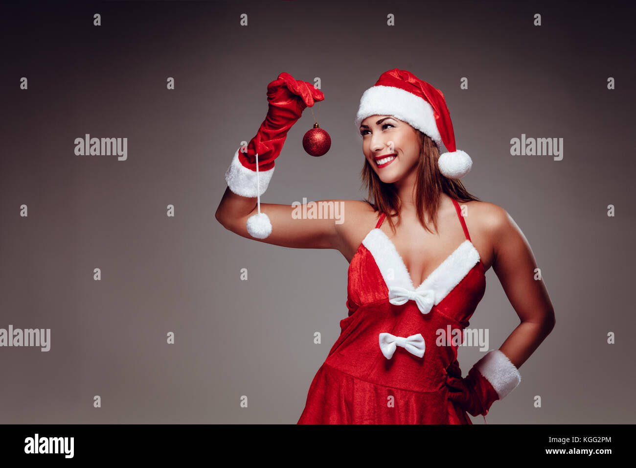 Bella giovane donna in santa claus costume rosso tenendo palla di Natale. Foto Stock