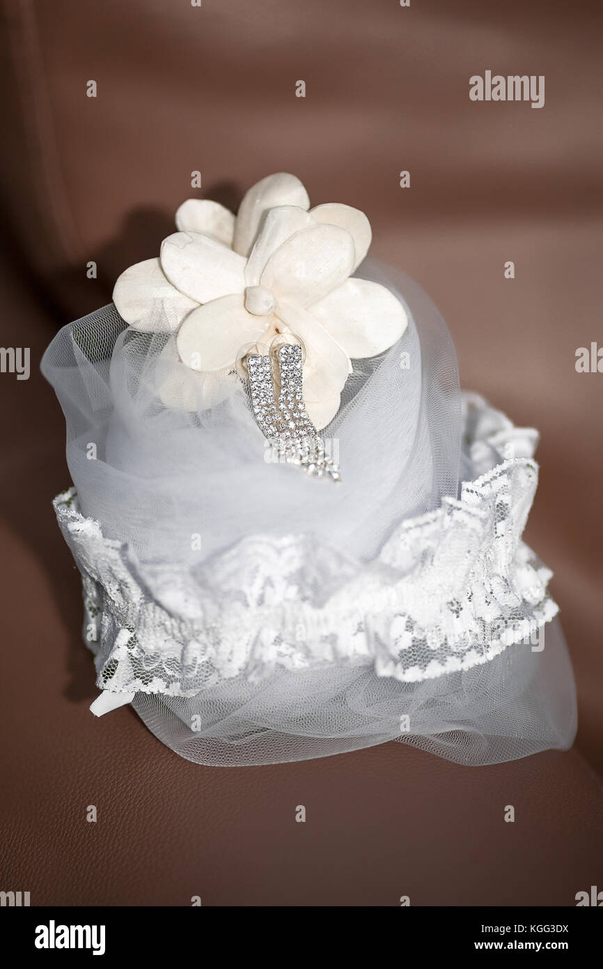 Bridal Accessories - legare giarrettiera, cristallo argento orecchini pendenti e velo posto su divani in pelle marrone Foto Stock
