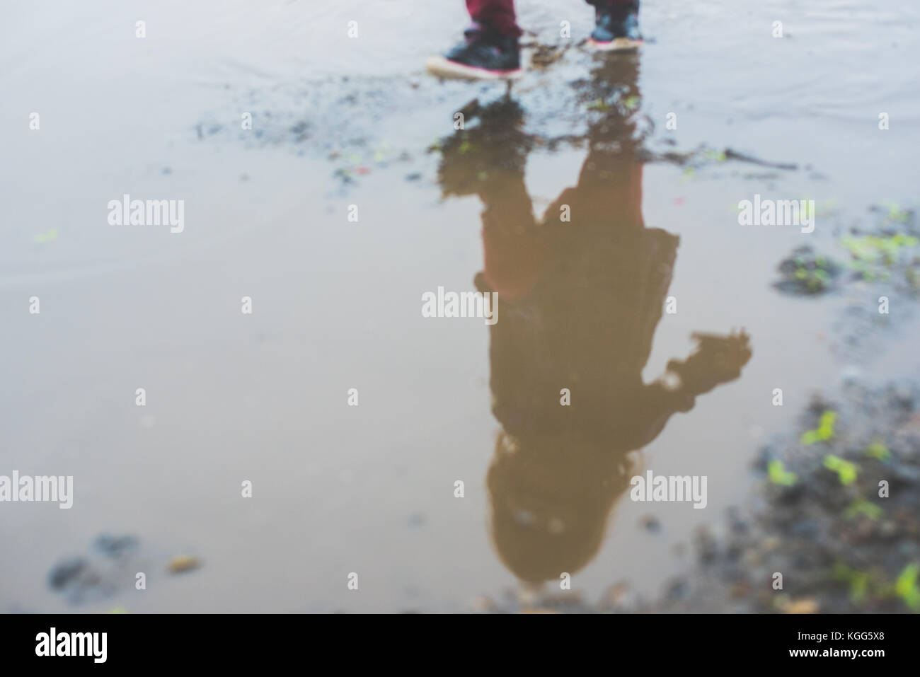 Bambino a camminare in una pozza di fango Foto Stock