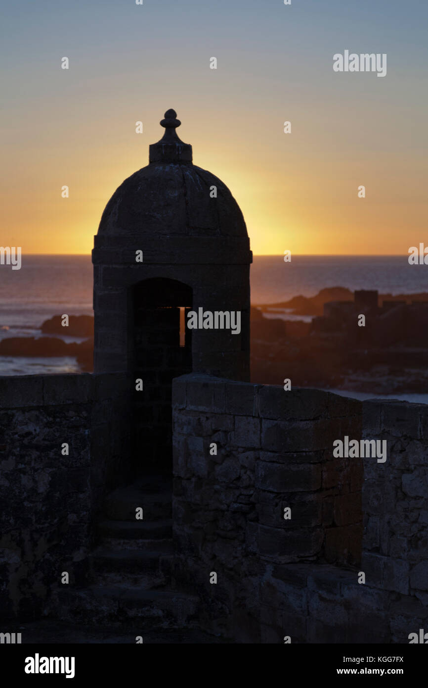 Marocco Essaouira, sulla parte superiore del portoghese torre di avvistamento al Porto di silhouette al tramonto, che guarda al mare. Foto Stock