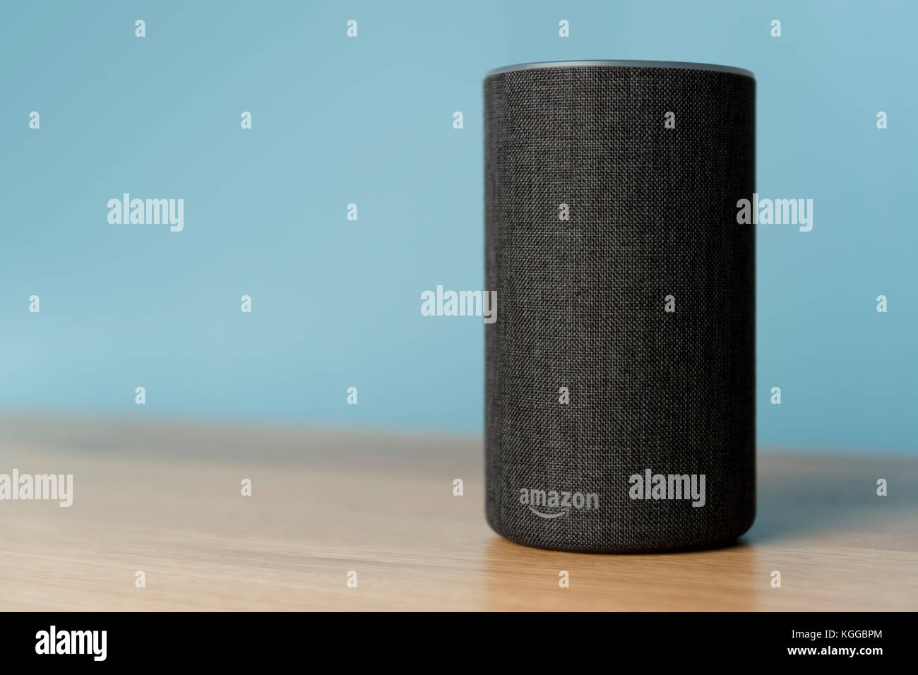 Il 2017 Rilascio di un carbone Amazon eco (di seconda generazione) smart speaker e assistente personale Alexa sparato contro un tavolo in legno e muro di blu. Foto Stock