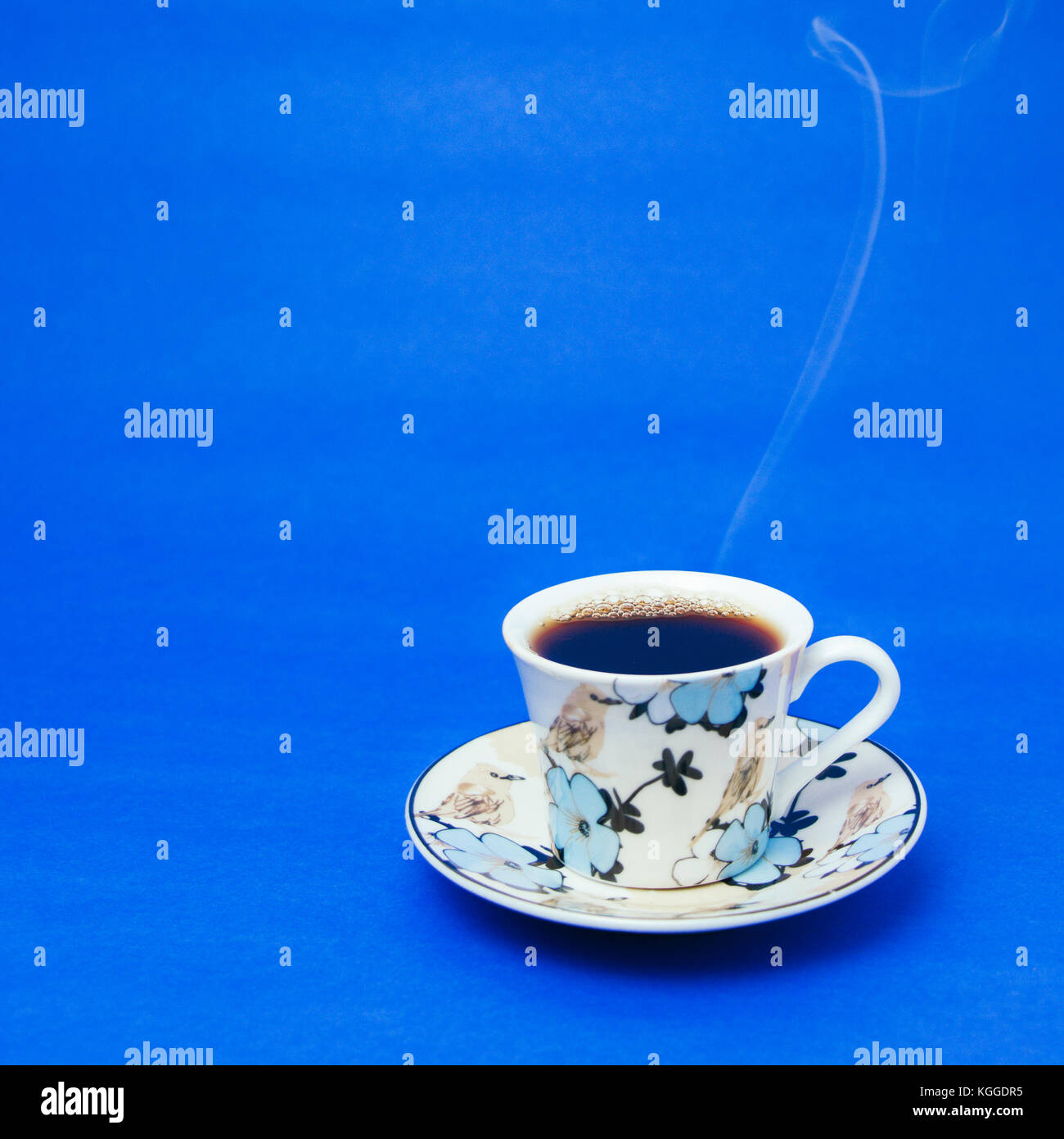 Tazza blu con caffè a vapore. Fumo morbido. Sfondo blu. Foto quadrata Foto Stock