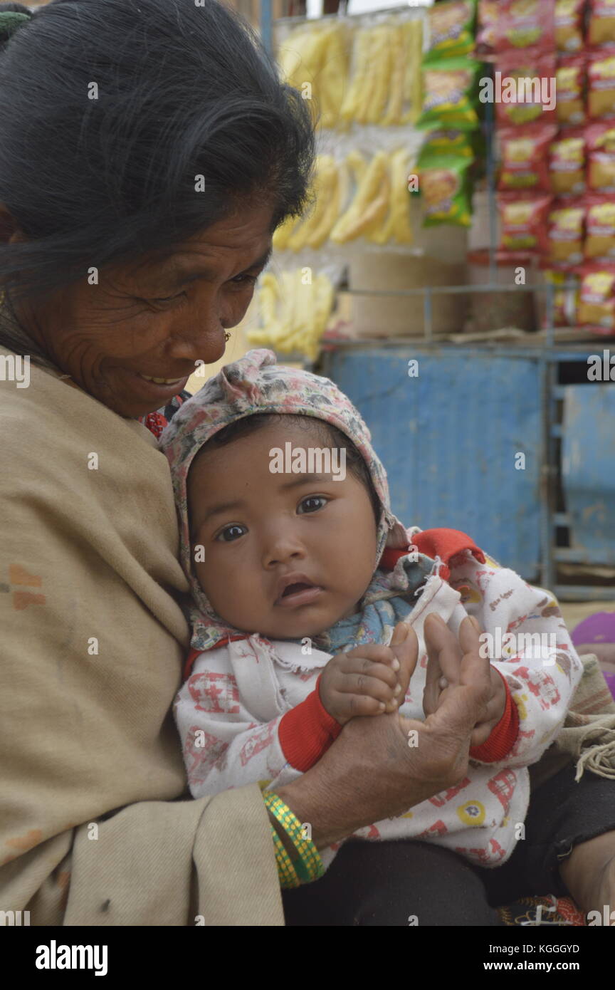 Vecchia nonna nepalese con nipote in grembo. tenendo mani e piedi. A Panauti, Nepal. bambino. bei occhi marroni. Foto Stock