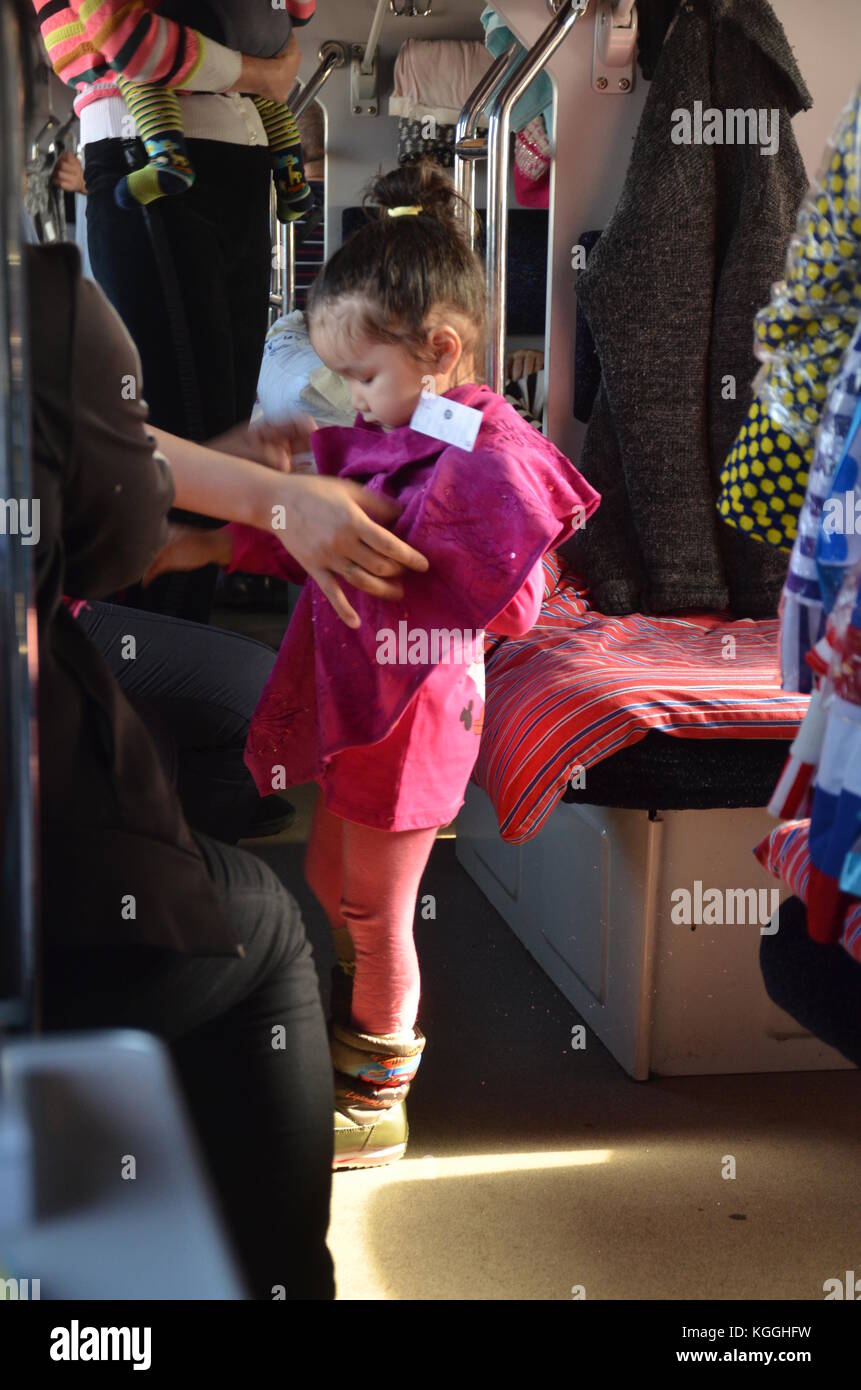 Bambina kazaka vestito su un treno russo platzkart in Kazakistan. Bazaar / mercato in treno. venditori di abbigliamento. venditori di strada. via della seta. Foto Stock