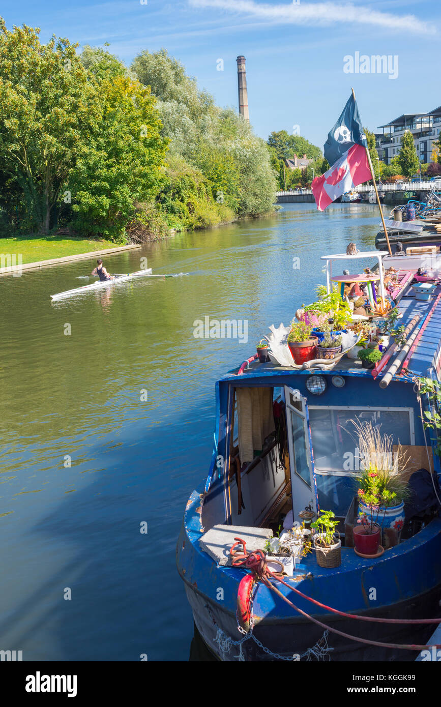 Chiatta per case galleggianti e studenti che regnano su un unico scull sul fiume Cam a Cambridge, Inghilterra, Regno Unito Foto Stock