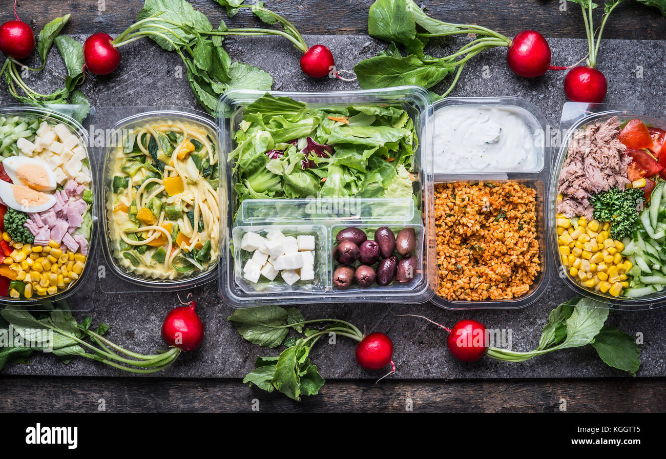 Varietà di pulire dieta insalate in confezione in plastica verde e nastro di misurazione su sfondo rustico, vista dall'alto. sano cibo pulito concetto. Foto Stock