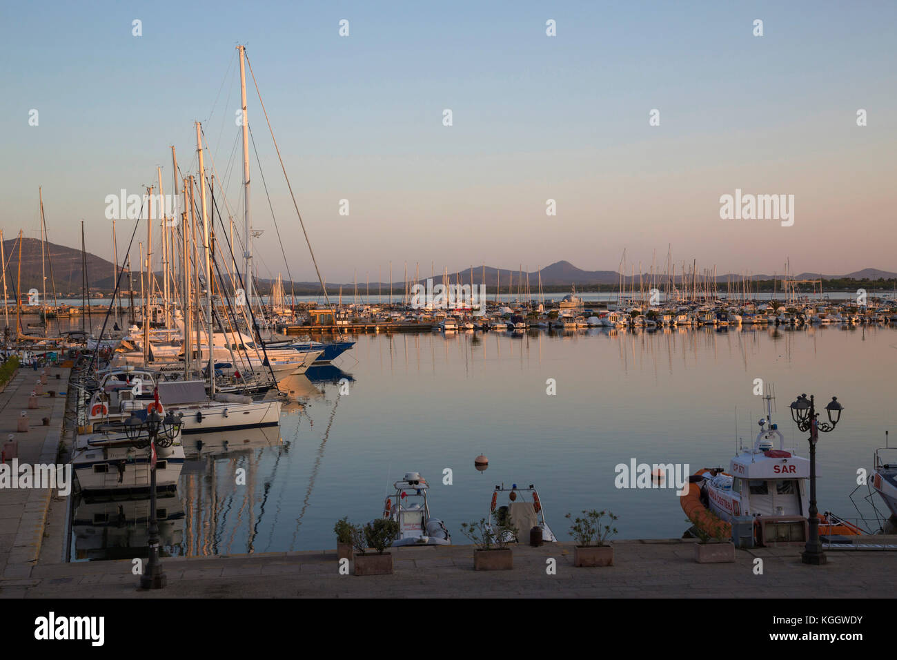 Alghero yacht bacino con barche ormeggiate in acque calme al mattino presto Foto Stock