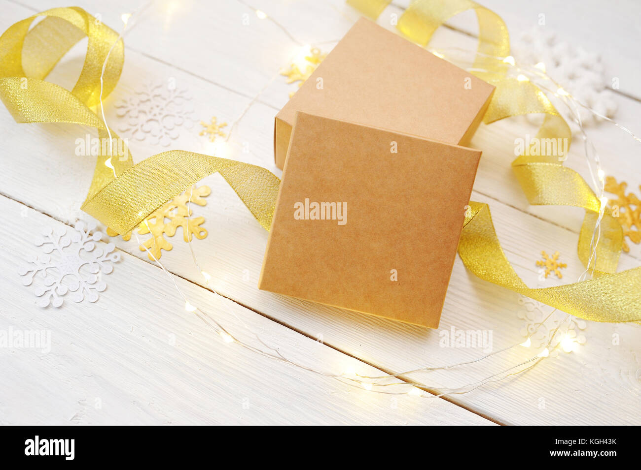 Composizione di natale mockup. scatola su uno sfondo di fiocchi di neve, un albero di Natale, un nastro d'oro Foto Stock