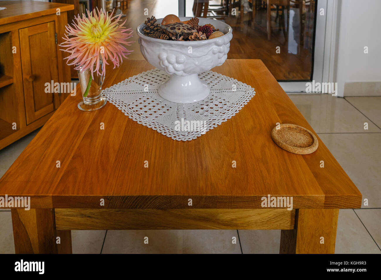 Oak tavolino con coaster, ciotola e dalhia fiore nel vaso. Soggiorno moderno closeup. Foto Stock