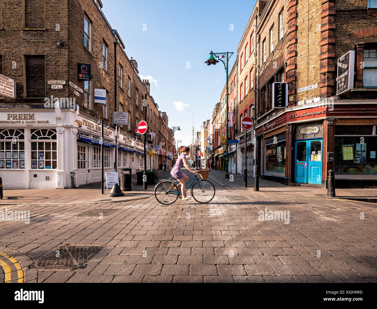 Attraversamento di bicicletta Hanbury Street e Brick Lane presto su una soleggiata mattina d'estate sulla strada verso la città di Londra Foto Stock