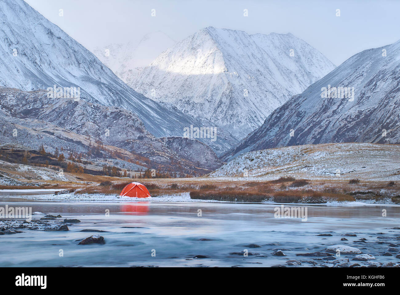 Inverno o tardo autunno in montagna, solitaria di campeggio e di un fiume o di un lago. Tenda Rossa si trova sulla sponda del fiume. Il terreno presenta per essere rocky highland w Foto Stock