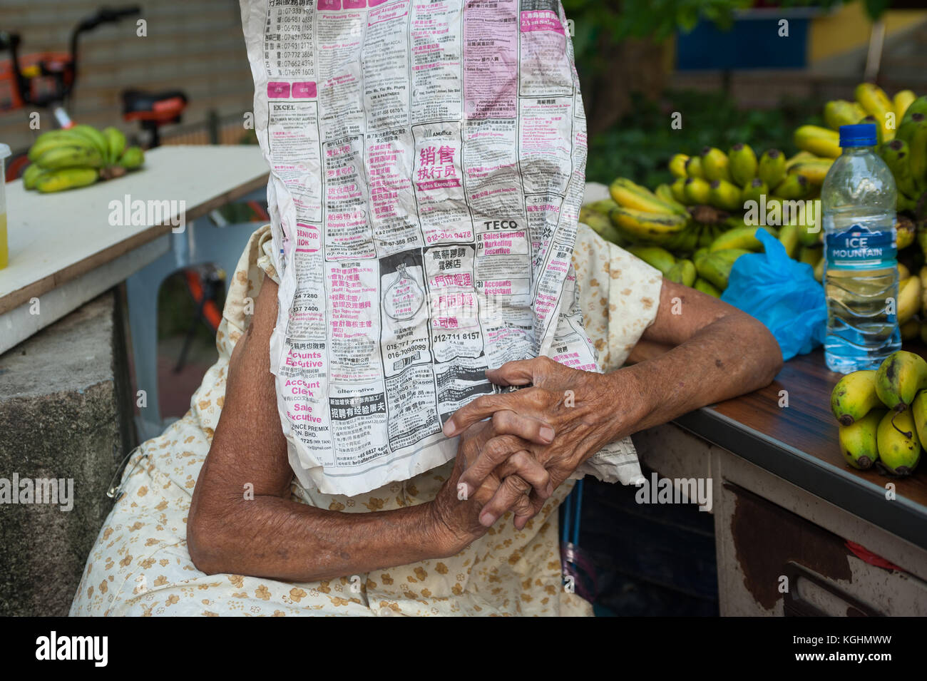 03.11.2017, Singapore, Repubblica di Singapore, in Asia - Una donna anziana che vende le sue banane a Singapore il quartiere Chinatown si nasconde dietro un giornale. Foto Stock