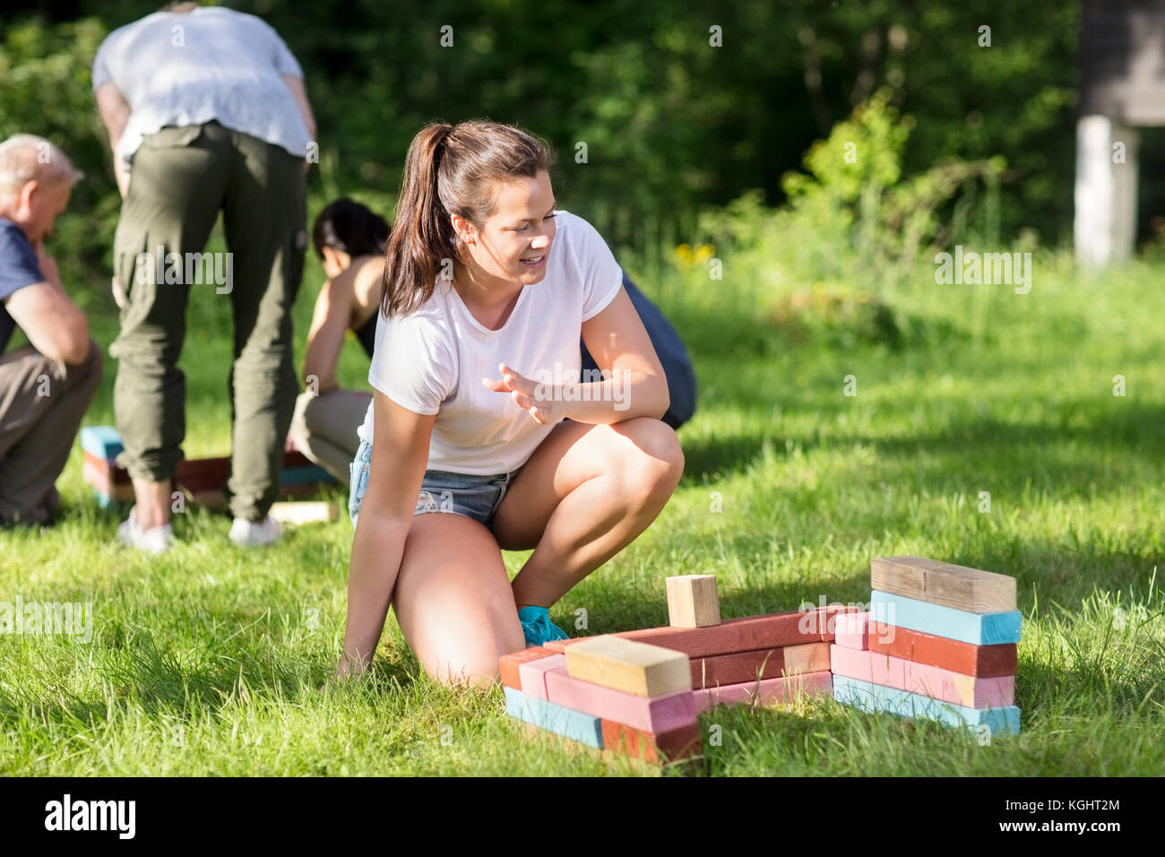Donna accovacciata da blocchi di costruzione mentre gli amici nella pianificazione di bac Foto Stock