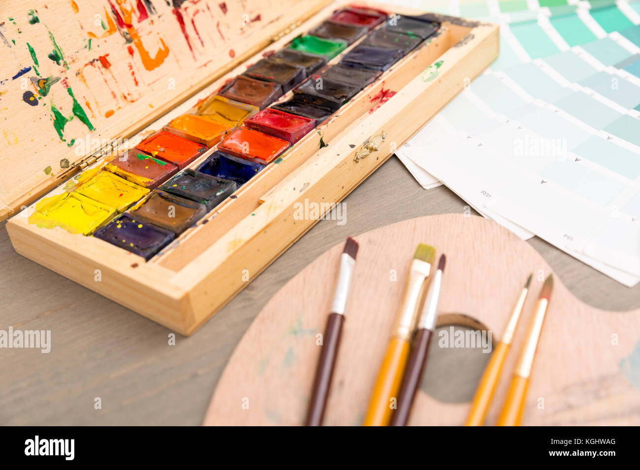 Vernici per disegno, tavolozza e pennello su uno sfondo di legno Foto Stock