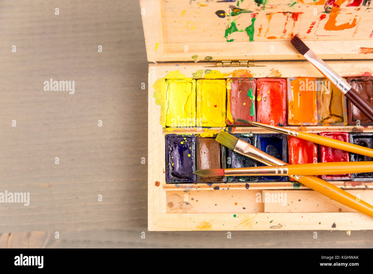 Vernici per disegno, tavolozza e pennello su uno sfondo di legno Foto Stock
