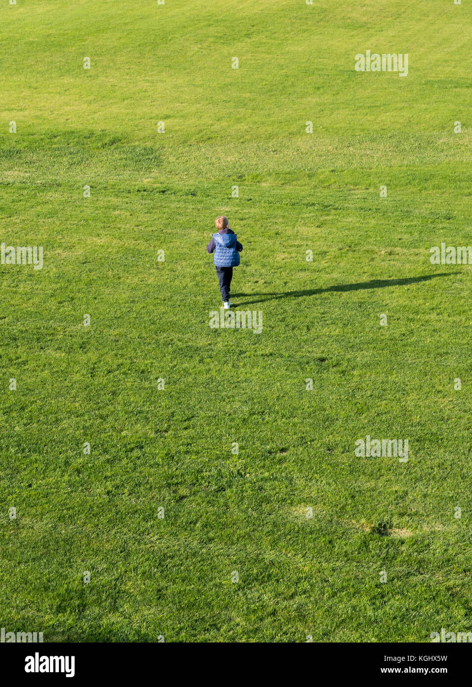 Piccolo Ragazzo in esecuzione su erba verde fiield outdoor Foto Stock