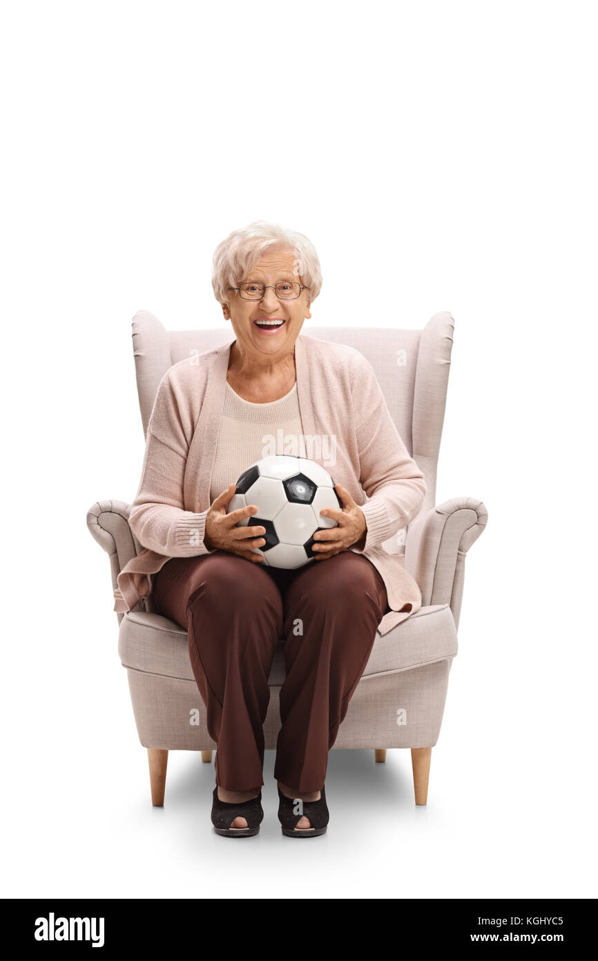 Allegra donna anziana con un calcio seduto in poltrona e guardando la telecamera isolata su sfondo bianco Foto Stock