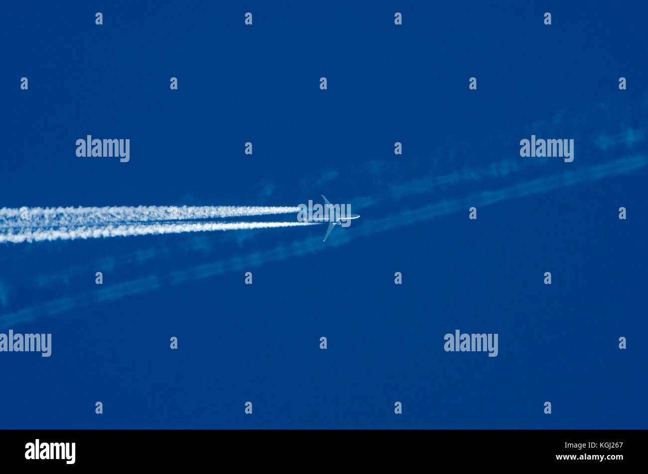 Trasporti Il concetto di concorrenza: un getto di attraversamento aereo altro piano white contrail contro il cielo blu con uno sfondo con spazio di copia Foto Stock