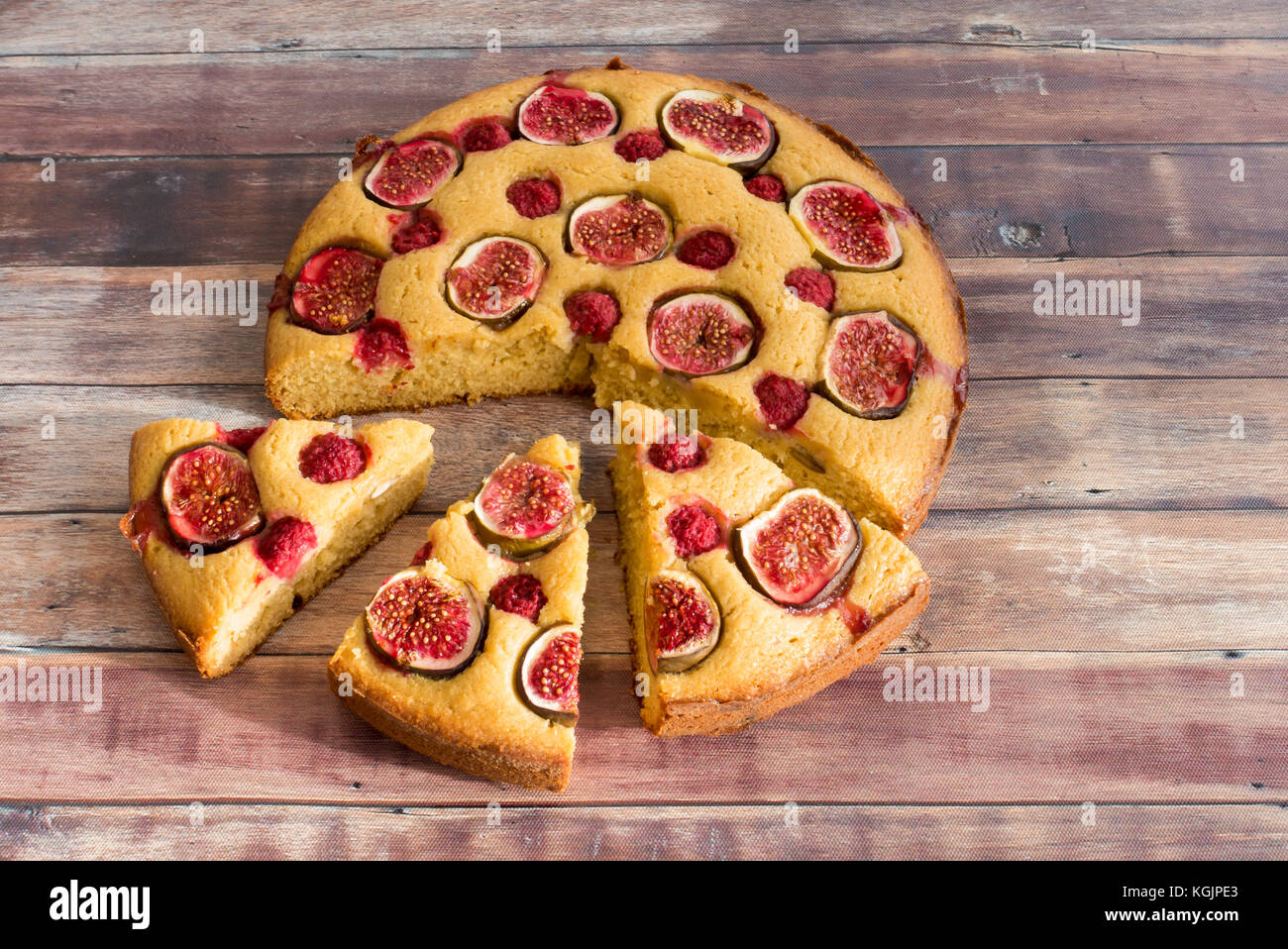Fig e lampone fette di torta di mandorle e miele a smalto su legno marrone scuro dello sfondo con copia spazio. Foto Stock