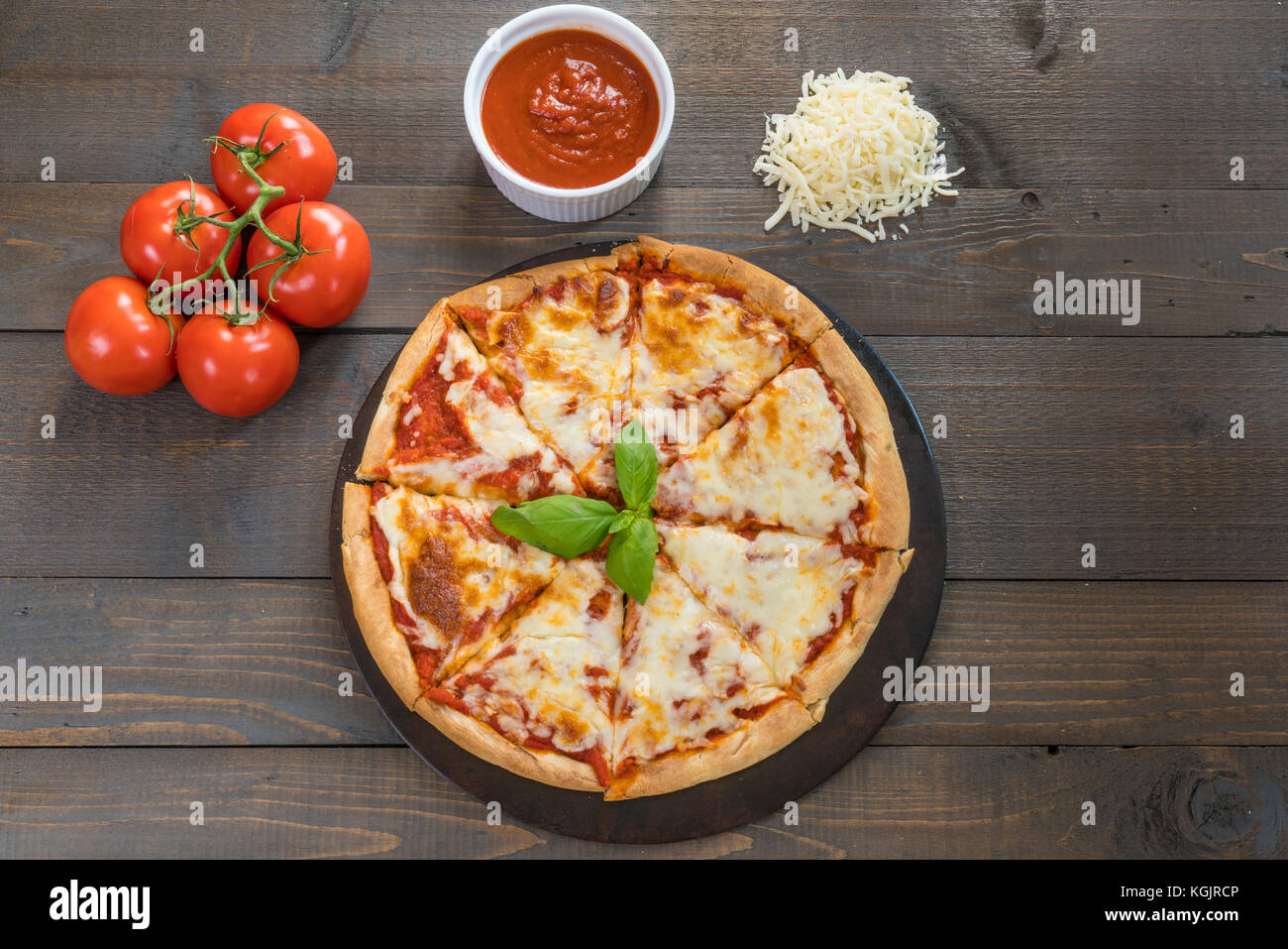 Fresca pizza calda sul tavolo di legno con ingredienti Foto Stock