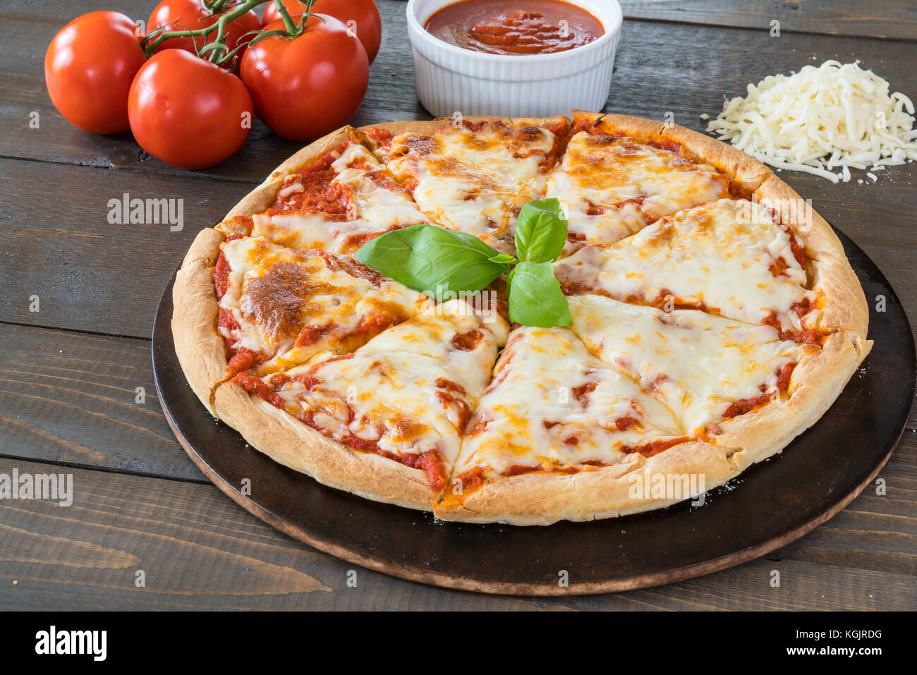 Fresca pizza calda sul tavolo di legno con ingredienti Foto Stock