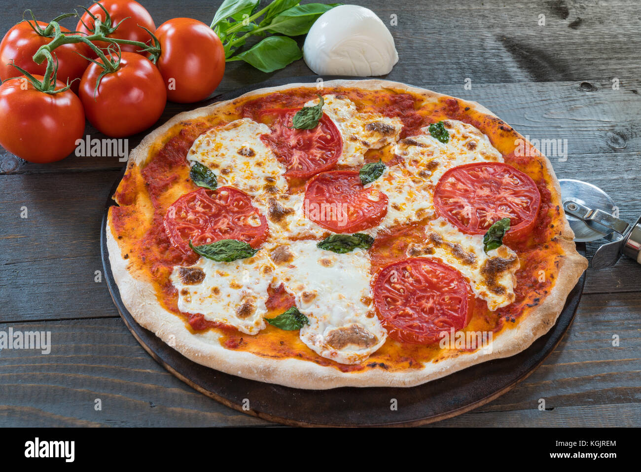 Fresca pizza calda sul tavolo di legno con ingredienti Foto Stock