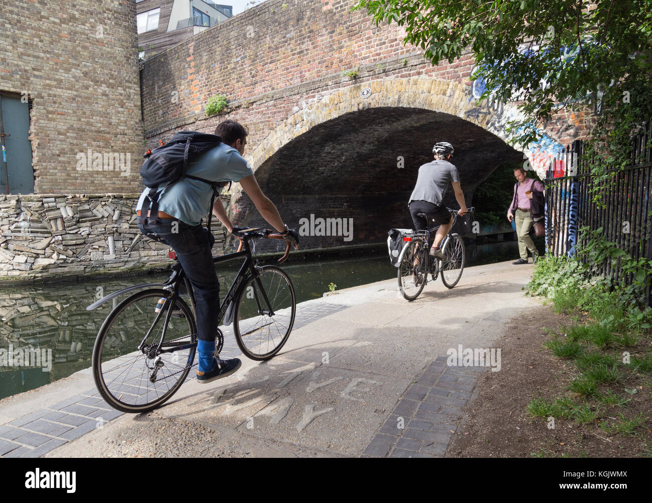 I ciclisti escursioni in bicicletta verso il ponte sul canale di arco con zona pedonale a piedi nella direzione opposta sulla strada alzaia dal Regent's Canal in haggerston, East London Foto Stock