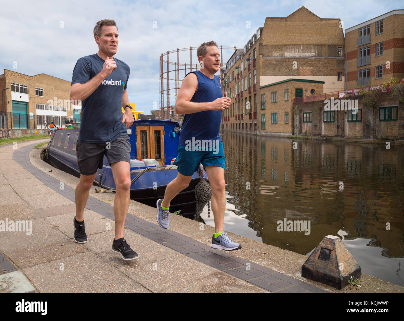 Due maschi giovani praticanti di jogging correre insieme lungo la strada alzaia dal Regent's Canal a Hackney, a est di Londra, Regno Unito Foto Stock