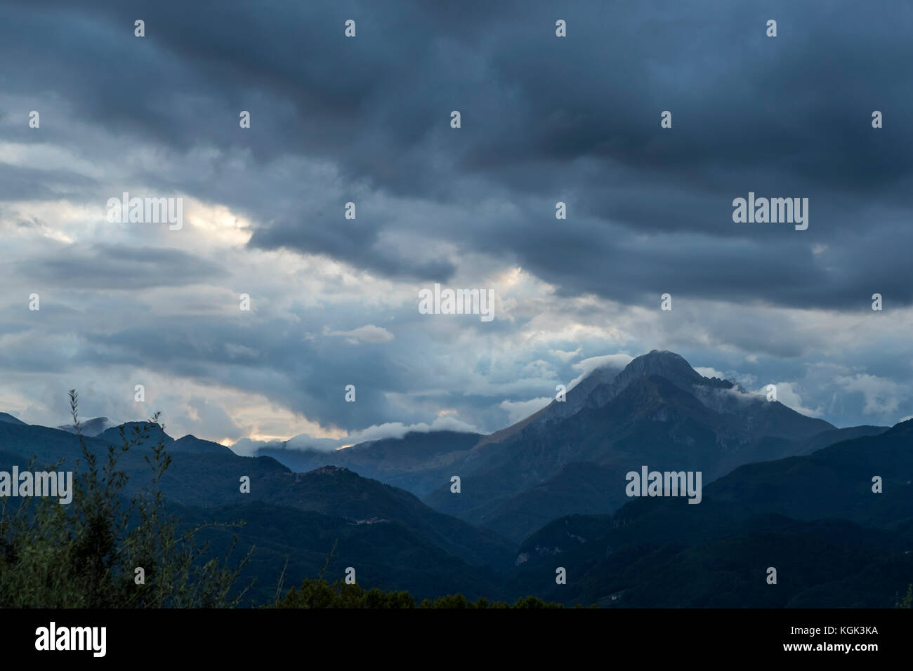 Drammatico il cielo al tramonto con la Pania della Croce al vertice della montagna nelle Alpi Apuane, Italia. Visto dal duomo di Barga. Foto Stock