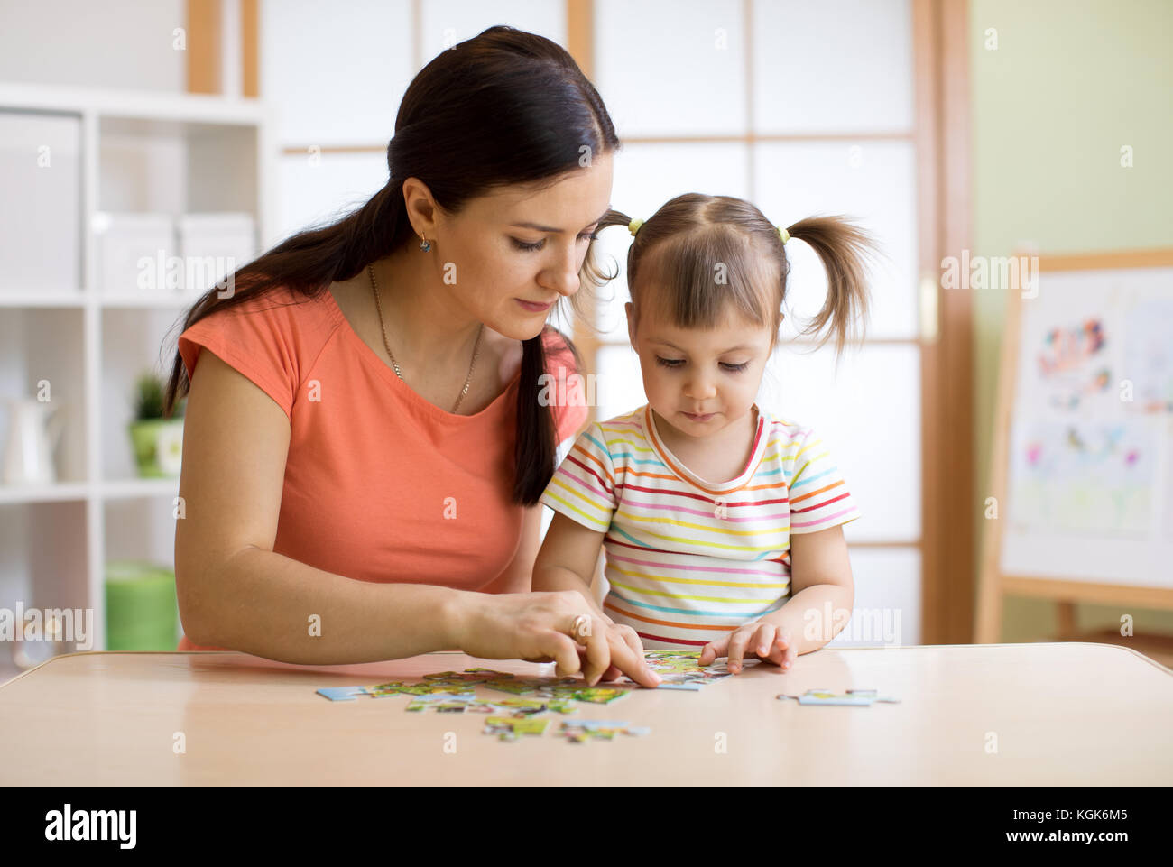 Madre e figlia a giocare a casa. essi assemblaggio di puzzle. Foto Stock