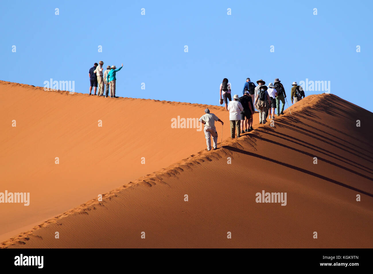 I turisti a camminare su una duna rossa in sossuslvei, Namib Naukluft national park, Namib Desert, Namibia. Foto Stock