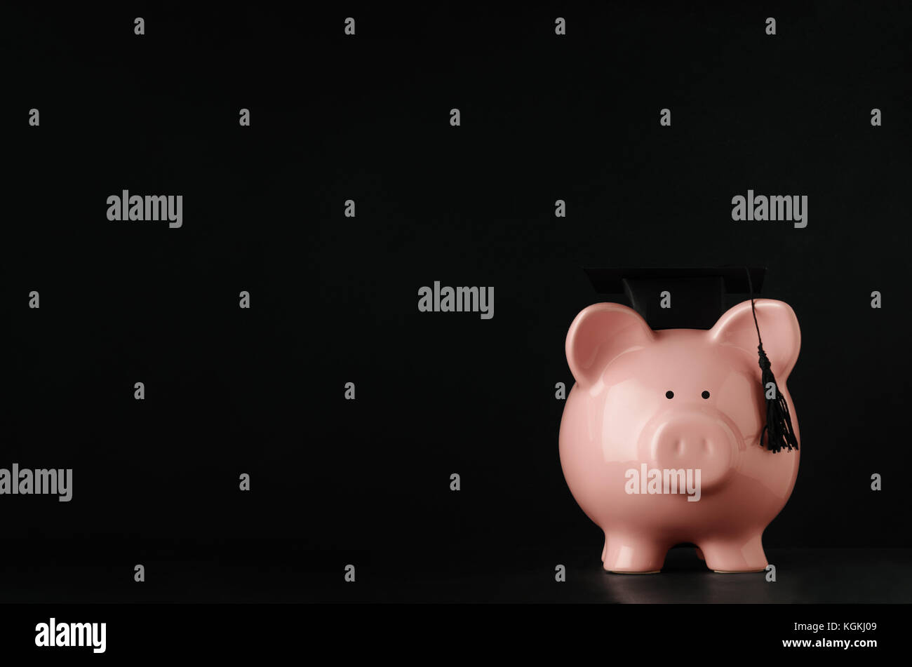 Rosa in ceramica salvadanaio rivolto verso la parte anteriore a livello degli occhi indossando un nero mortarboard. Blackboard sfondo con copia spazio a sinistra e sopra. Le tasse di iscrizione c Foto Stock