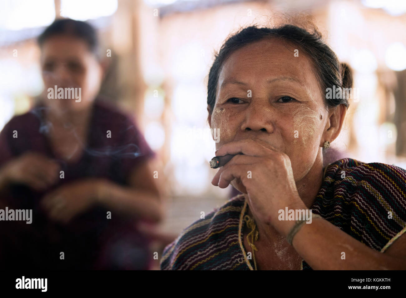 Vecchia donna birmano della tribù di bamar indossando thanaka e fumare un sigaro in kayin villaggio nei pressi di Hpa-an, kayin membro / karen stato, myanmar / BIRMANIA Foto Stock