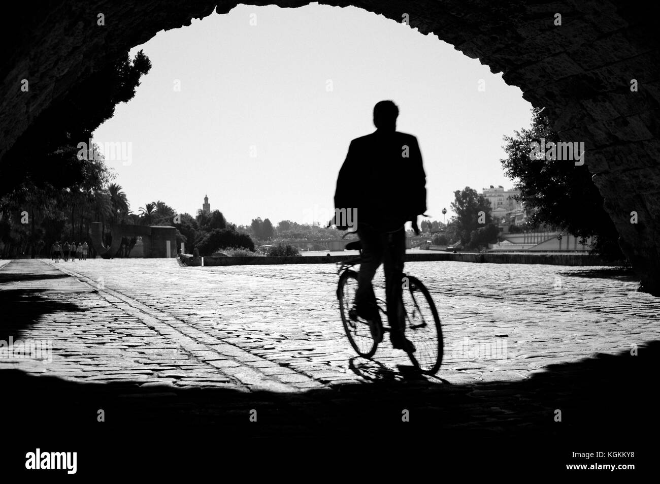 B&w la foto di un ciclista in sella al di sotto del ponte di Triana, Siviglia, Spagna Foto Stock