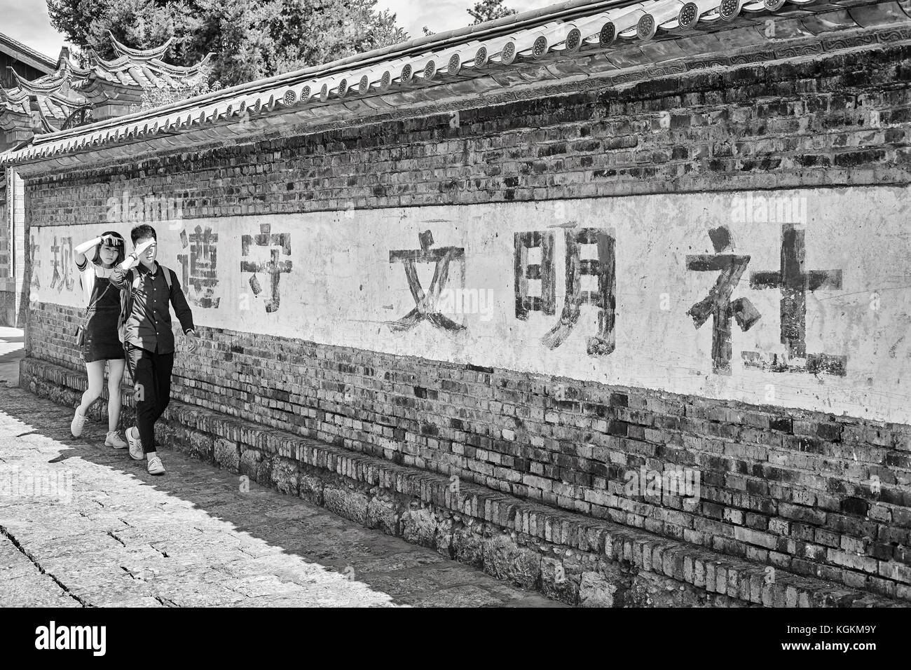 Lijiang, Yunnan, Cina - 28 Settembre 2017: giovani cinesi a piedi all'ombra di Dayan parete. Città vecchia di Lijiang è un sito Patrimonio Mondiale dell'UNESCO. Foto Stock