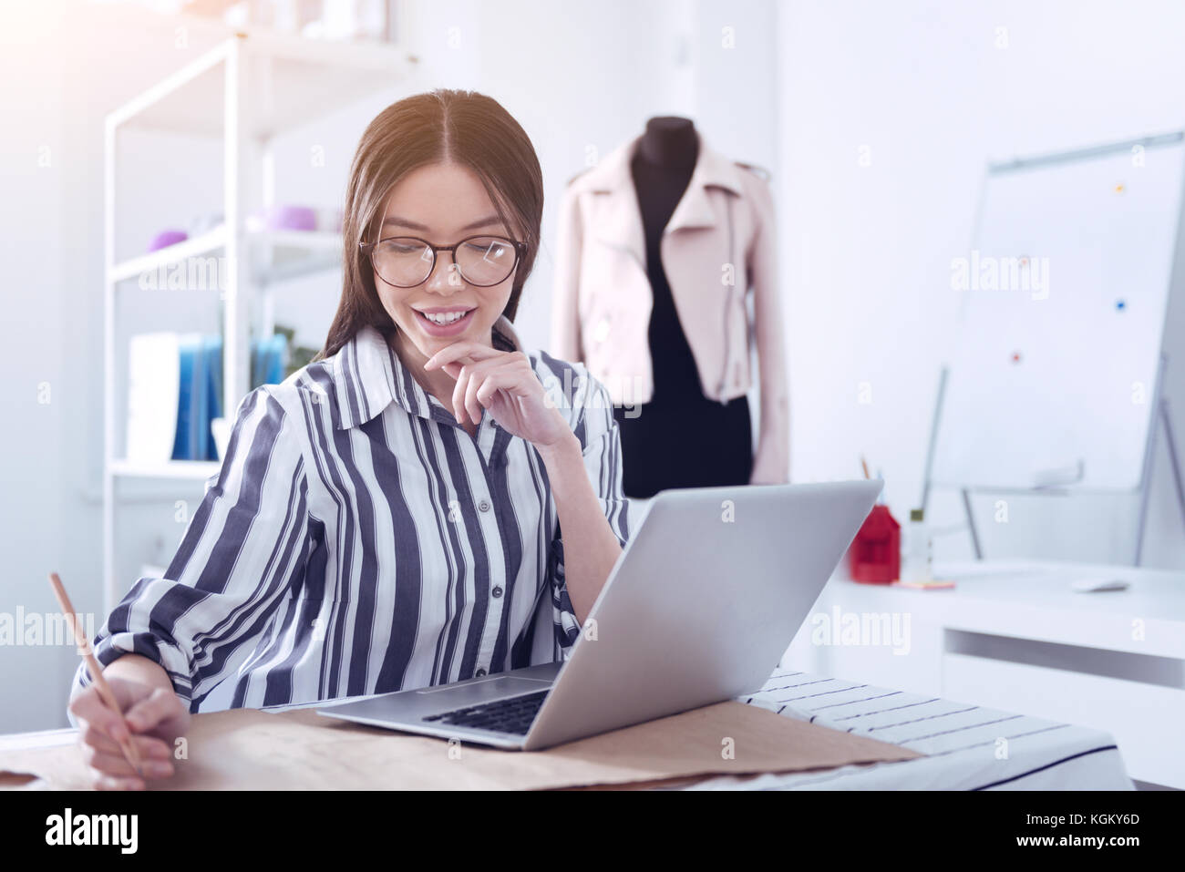 Donna sorridente con notebook rendendo note su un disegno Foto Stock