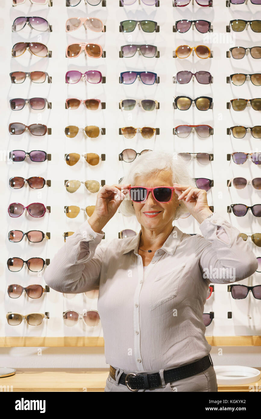 Ritratto di donna senior indossando occhiali da sole mentre si sta in piedi in negozio Foto Stock
