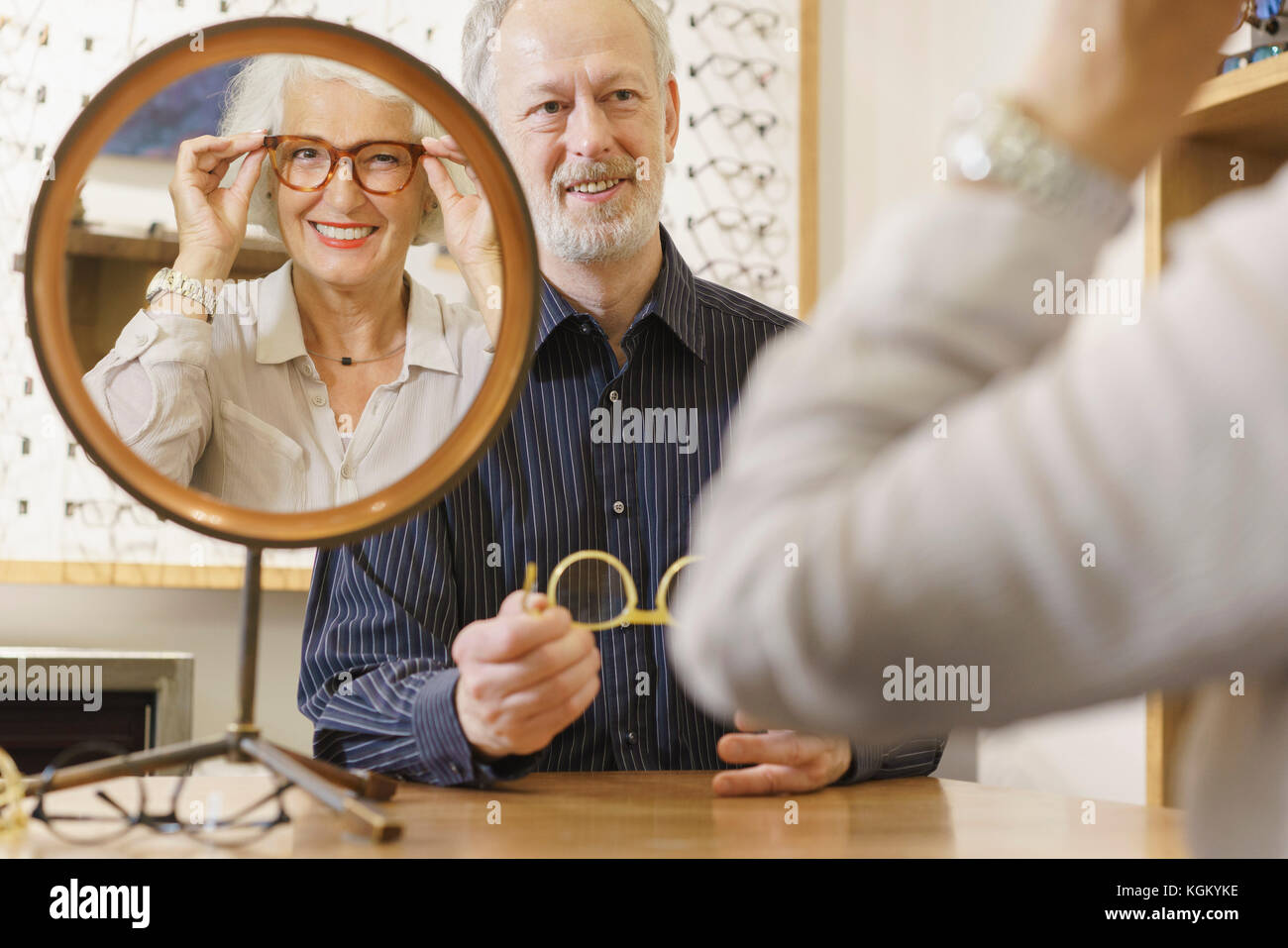 Ottico assistere donna sorridente nella scelta di occhiali in negozio Foto Stock