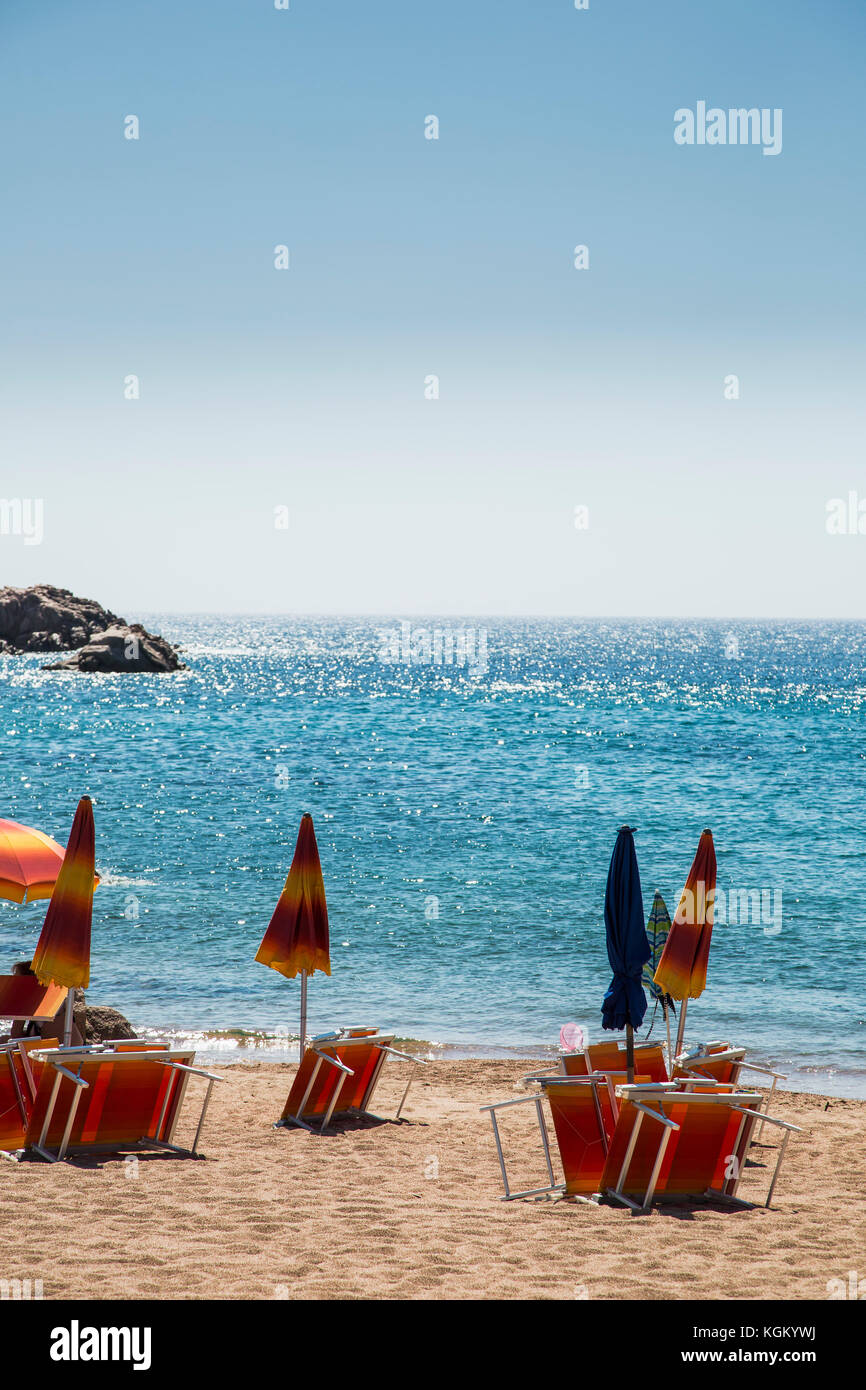 Chiuso di ombrelloni e sedie a sdraio in spiaggia contro il cielo blu e chiaro sulla giornata di sole Foto Stock