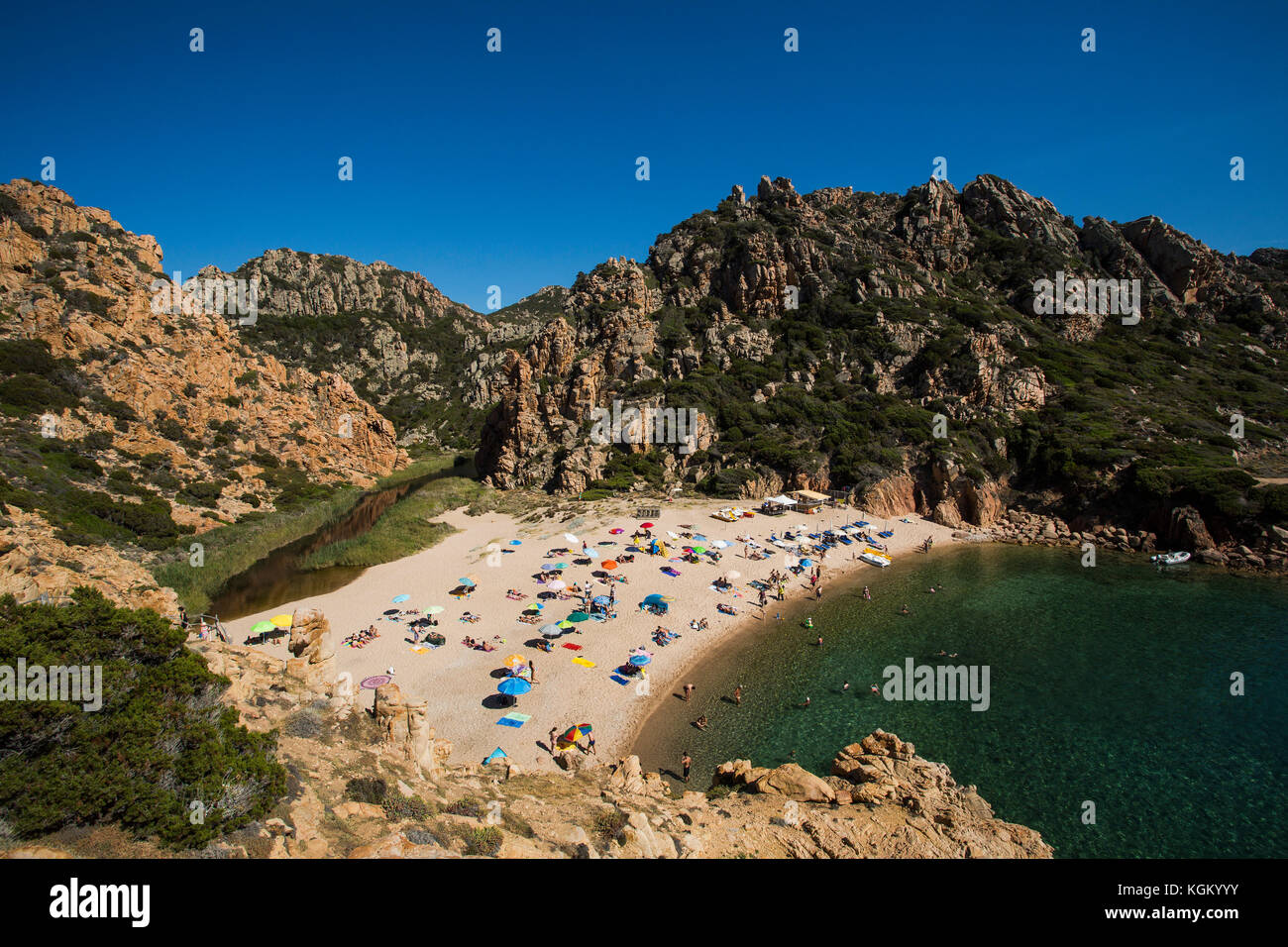 Vista panoramica della spiaggia e immerso in formazioni rocciose contro il cielo blu chiaro, Sardegna, Italia Foto Stock