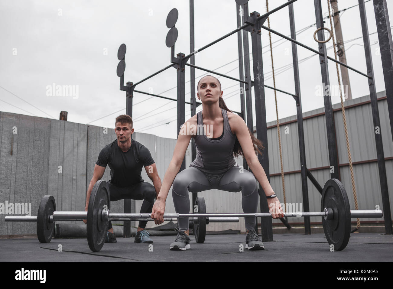 Lunghezza completa di determinato maschio e femmina atleta esercitando con barbells durante il training crossfit Foto Stock