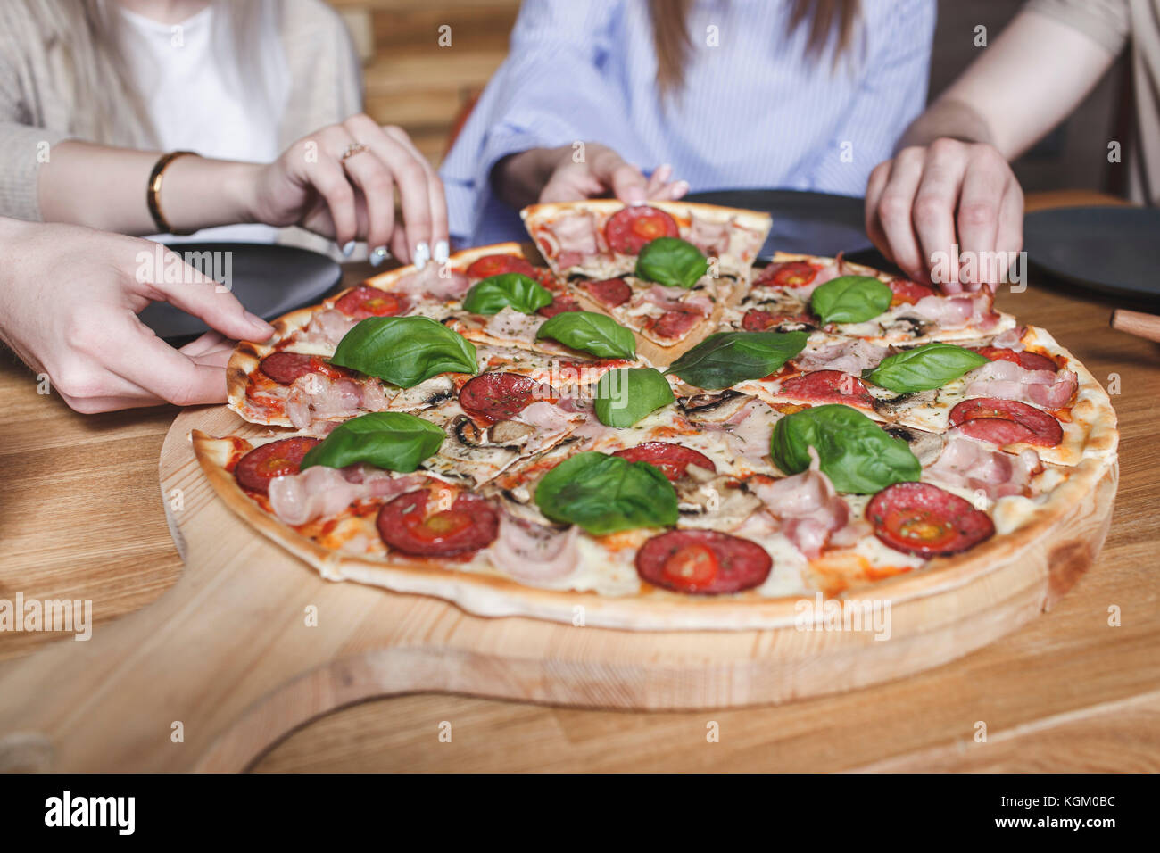 Immagine ritagliata di amici avente la pizza al ristorante Foto Stock