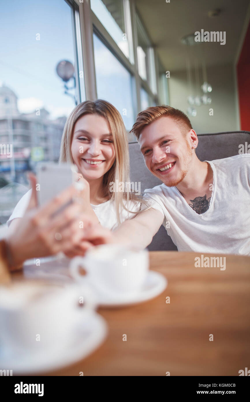 Felice coppia giovane tenendo selfie con il cellulare mentre seduti al ristorante Foto Stock