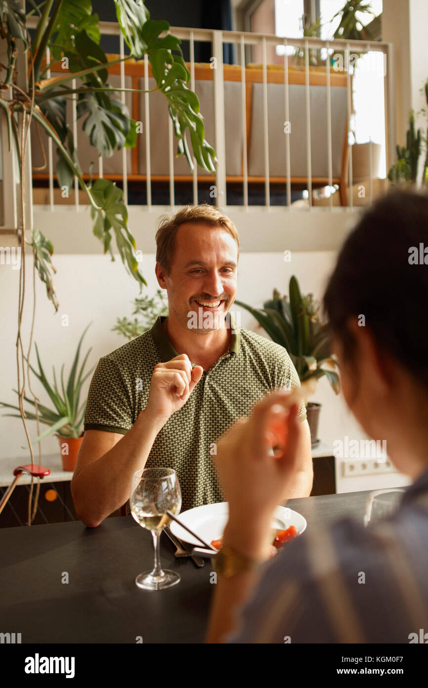 Uomo felice guardando la donna pur avendo il cibo al tavolo da pranzo in casa Foto Stock